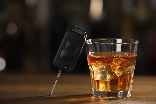 Car key beside a glass of alcohol